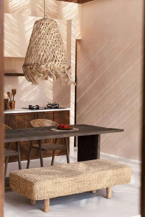 Waterhyacinth bank aan donkere houten tafel met rotan luster in boho interieur