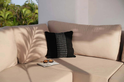 Kussen The Drizzle in zwart met wit patroon op beige buitenbank.