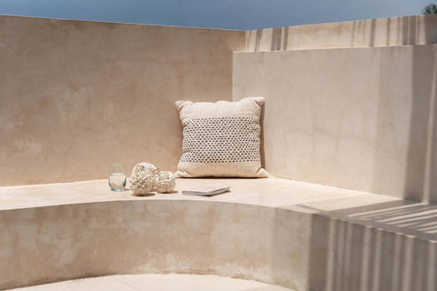 Beige en zwart kussen The Misty geplaatst op bank in buiteninterieur met boho sfeer.