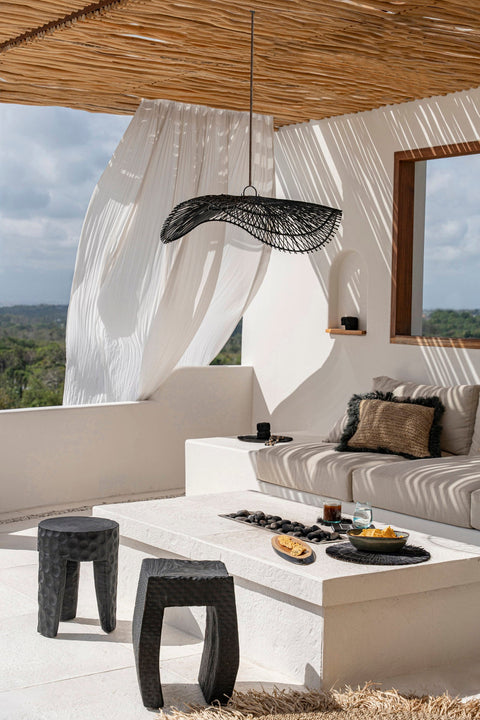 The Chapeau lamp van zwart rotan op zonnig overdekt terras.