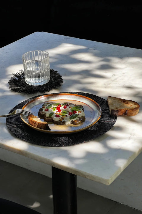Handgemaakte placemat The Beaded als deel van een gedekte boho tafel op terras.