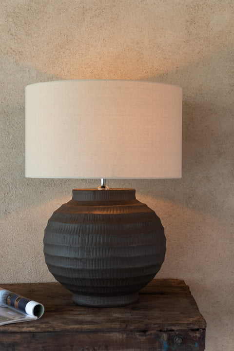 Tafellamp gestyled op donker houten kast tegen neutrale muur – rustgevende, natuurlijke sfeer