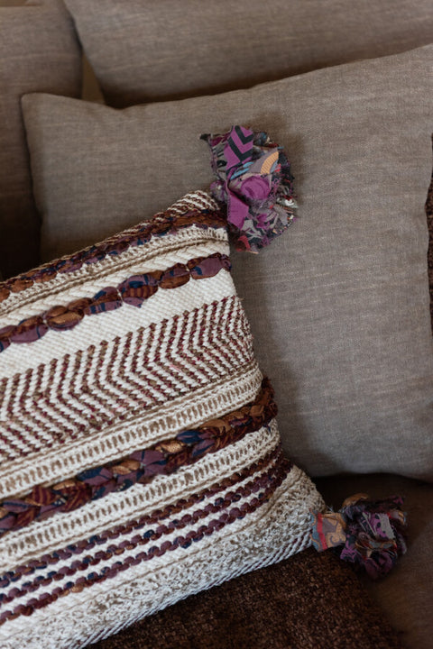 Interieurfoto van J-Line sierkussen 'Braided Chindi' in bruin, gestyled op een neutrale bank in een rustiek, boho-japandi interieur