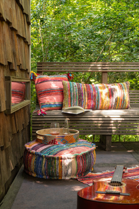 Kussen ‘Chindi Kwastjes’ buiten gestyled op bank met andere Chindi accessoires – kleurrijke boho setting met natuurlijke flair
