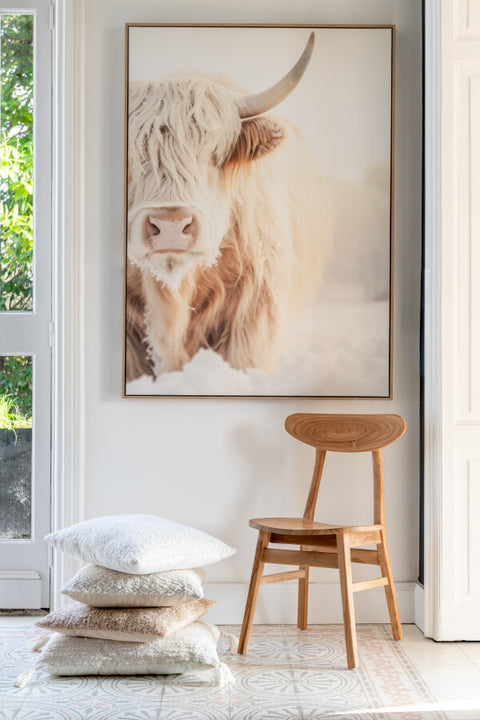 J-Line kussen ‘Cotton Cream’ als onderdeel van een gestylde stapel kussens naast houten stoel – natuurlijke, serene interieursfeer