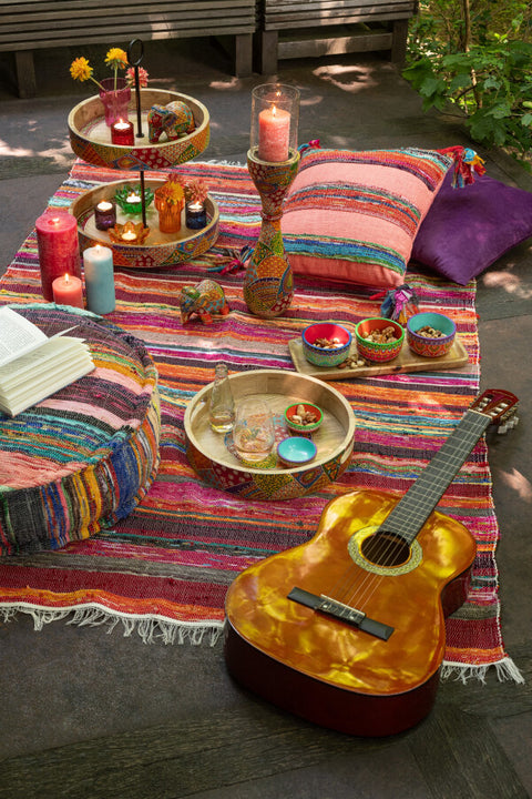 J-Line tapijt ‘Chindi’ buiten gestyled met kussens en accessoires uit dezelfde collectie – kleurrijke boho setting in natuurlijke sfeer