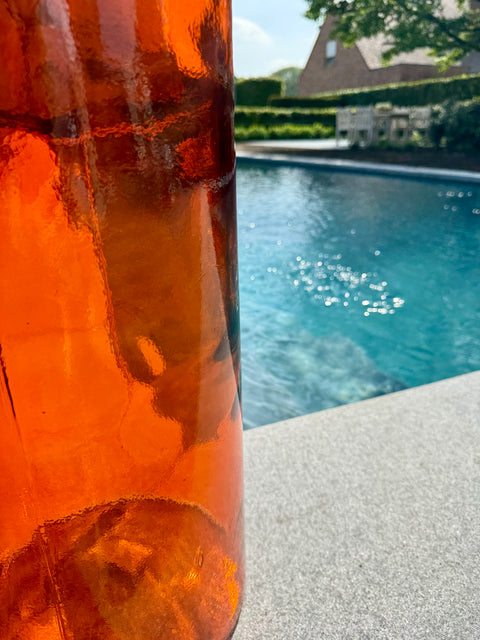 J-Line vaas ‘Color’ large gestyled aan het zwembad – zomerse setting met warme oranje glasdecoratie