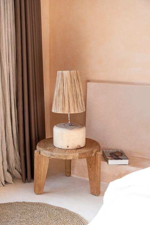 Koffietafel 'Wabi Sabi' gebruikt als nachtkastje naast een bed in serene, wabi-sabi geïnspireerde slaapkamer