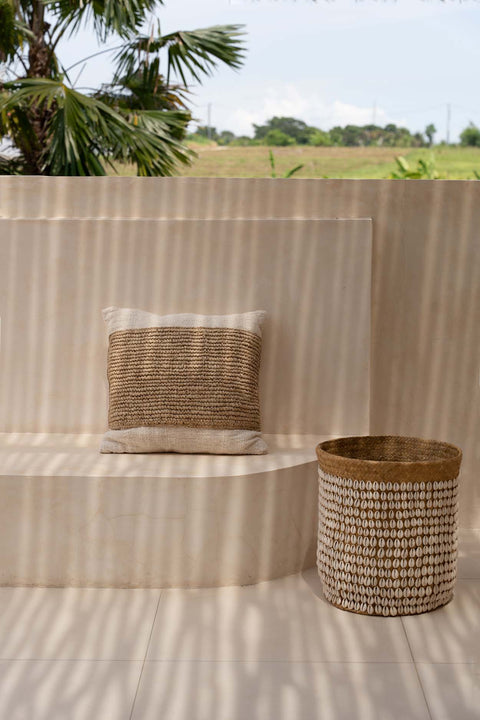 Kussenhoes ‘Raffia Stamp’ op houten buitenbank in zuiderse setting