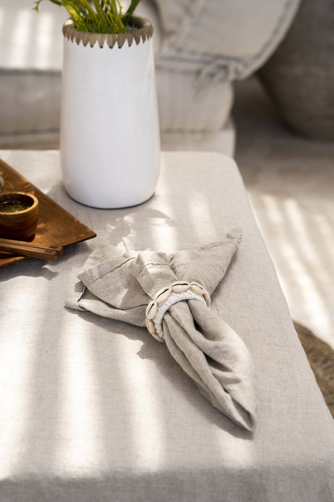 Beige servet naast een witte vaas, warme tafelsetting