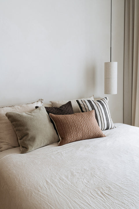 Gestreepte jacquard kussens gecombineerd met andere kussens op bed – Studio Femme