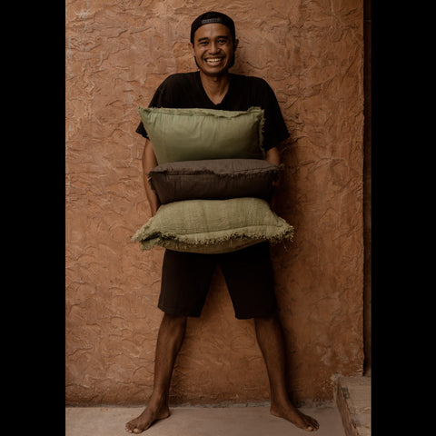 Man met meerdere sierkussens waaronder groen kussen The Jungle Fringe