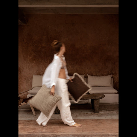 Vrouw houdt bruin wit kussen The Espresso Edge in boho interieur