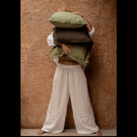 Vrouw met verschillende sierkussens waaronder groen kussen The Jungle Fringe