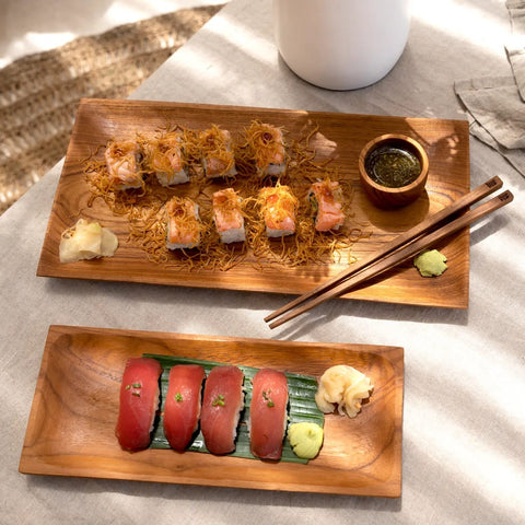 The Teak Root eetstokjes naast twee houten sushischotels
