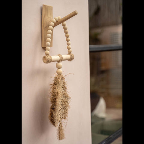 Naturelkleurige kapstokhaak aan een beige muur met een decoratieve ketting van rotan