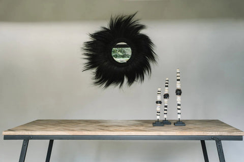 Zwarte Simba spiegel boven een houten wandtafel met decoratie.