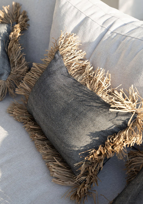 Bazar Bizar The Cotton Bonita kussen gestyled op een grijze stoffen bank in een warm en natuurlijk interieur.
