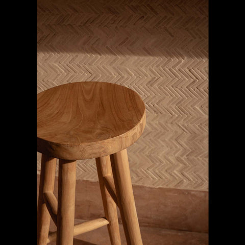 Detail van de The Kedut barstoel van teakhout voor een beige bar