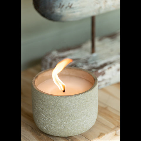 Brandende buitenkaars in cement pot op houten tafel