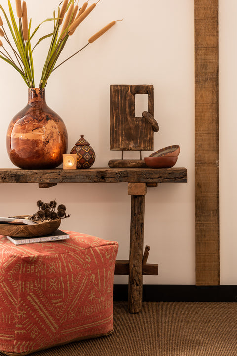 J-Line console Rough tegen witte muur, gestyled met oranje vaas en decoratie.