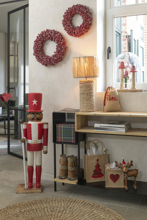 Kleine en grote J-Line kransen met rode bessen boven console met kerstdecoratie.