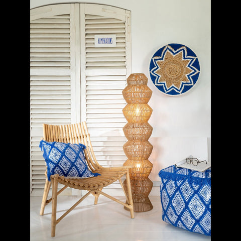 J-Line Oriental kussen gecombineerd met een rotan lamp, bijpassende poef en Banana Twig Dark Blue muurdecoratie.