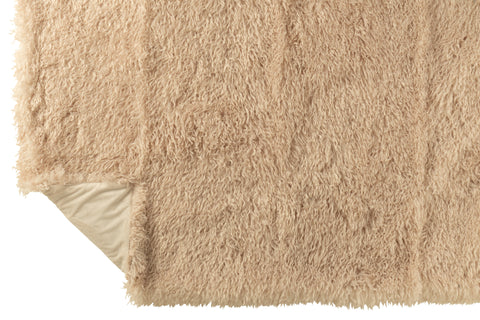 Beige fluffy plaid opengeplooid met omgeslagen hoek voor structuurdetail.