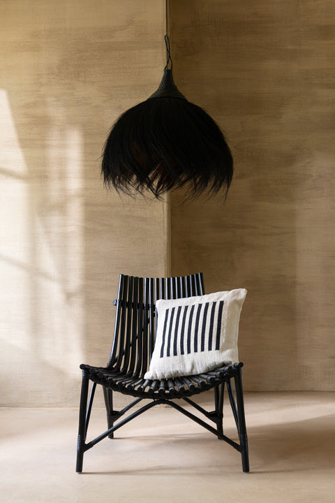 J-Line stoel Rattan in beige boho interieur met zwarte rotan lamp erboven.