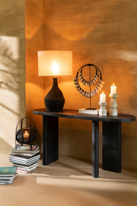 J-Line tafel Negro tegen oranje muur, gestyled met lamp en decoratie.