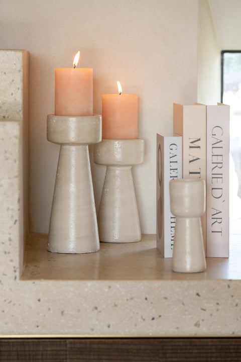 J-Line kandelaars 'Olina' in small, medium en large samen gepresenteerd op een rek tussen decoratieve boeken, in zachte travertin-look