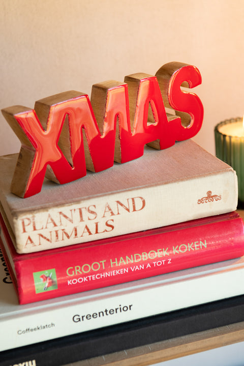 J-Line Ornament Xmas geplaatst op een stapel boeken, houten kerstdecoratie met rode afwerking