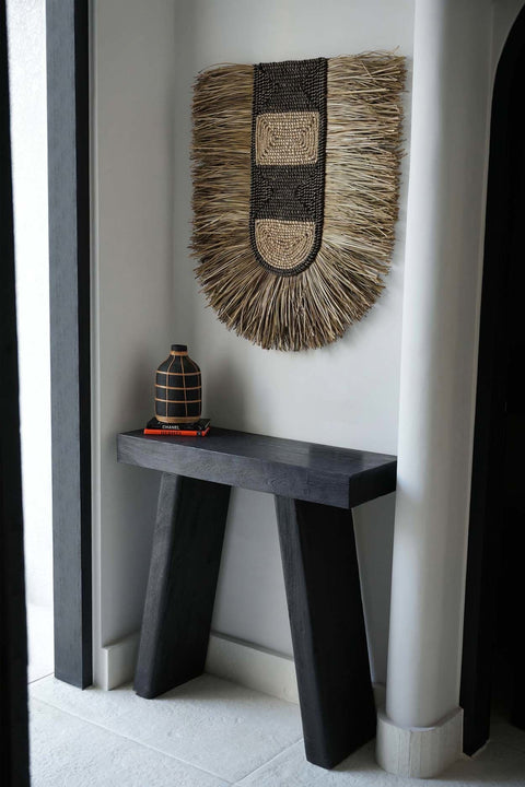 The Dada muurdecoratie boven een zwarte console tegen een witte muur