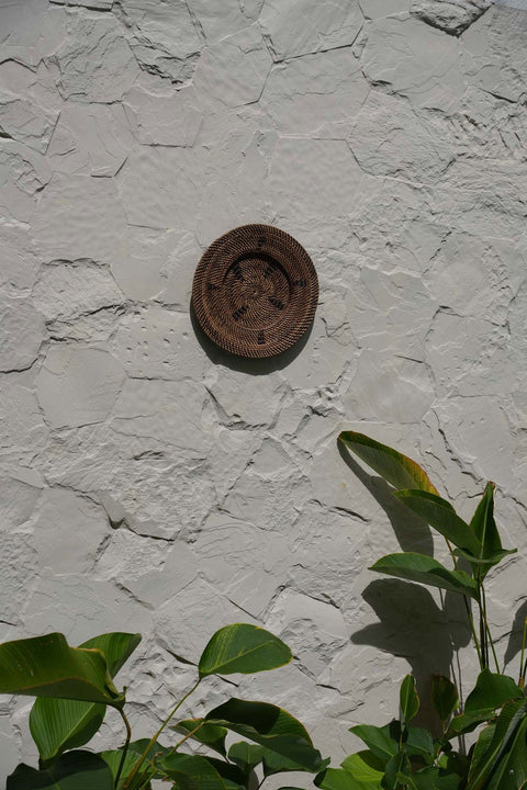 The Jasmine Plate muurdecoratie tegen een witte muur met groene planten