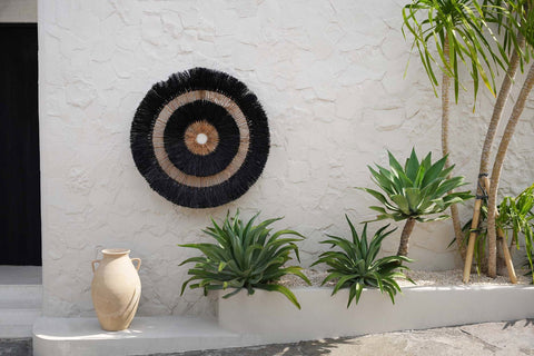 The Maurea muurdecoratie tegen een muur met groene planten eronder