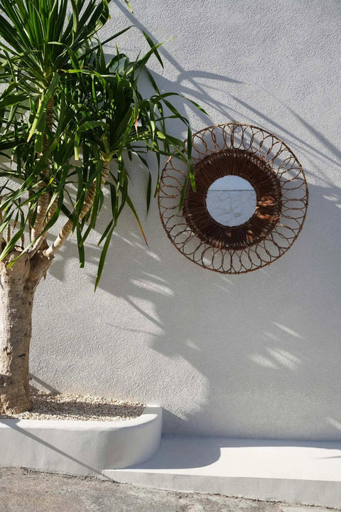 Montezuma spiegel gestyled tegen een buitenmuur met een grote groene plant