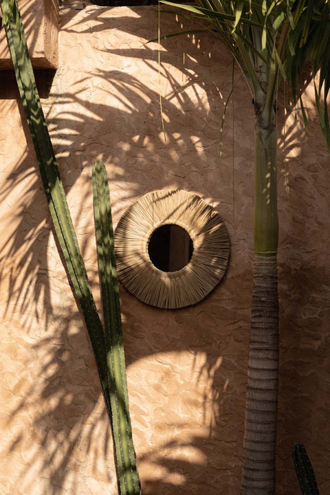 The Alang Alang Large spiegel tegen een muur met tropische planten