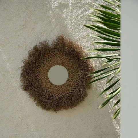 Bazar Bizar spiegel tegen een beige muur in een natuurlijke setting