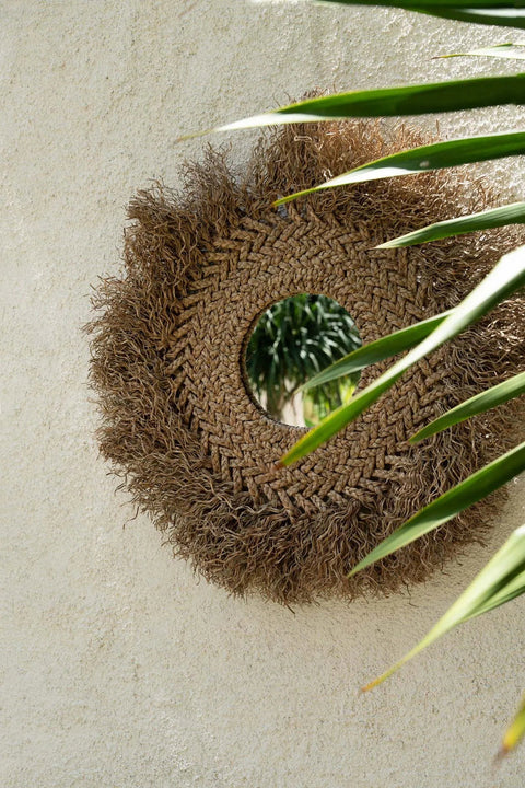 The Early Monday Mirror gecombineerd met een groene plant tegen een beige muur