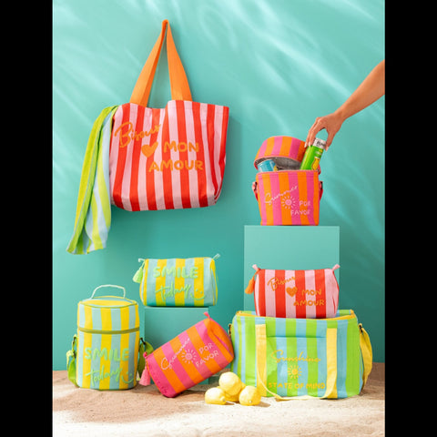 Opgevouwen Sunshine Smile strandlakens tussen kleurrijke strandtassen en zomeraccessoires