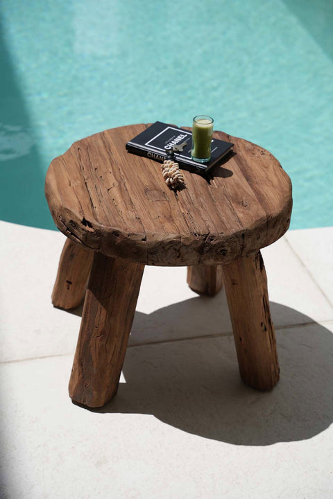 Naturel teakhouten The Marbunta bijzettafel met een boek naast het zwembad