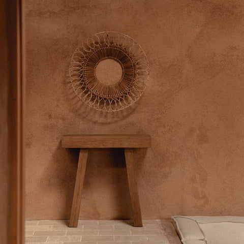 Naturel teakhouten The Stance console met decoratie tegen een bruine muur